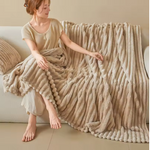 Plush striped throw blanket styled on a living room couch.
